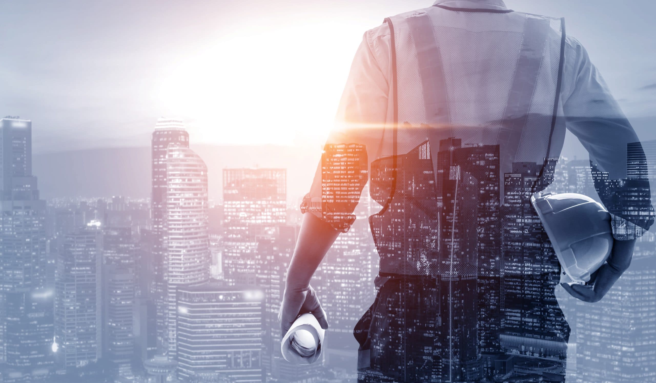Engineer holding a hard hat and drawings, overlooking a city skyline